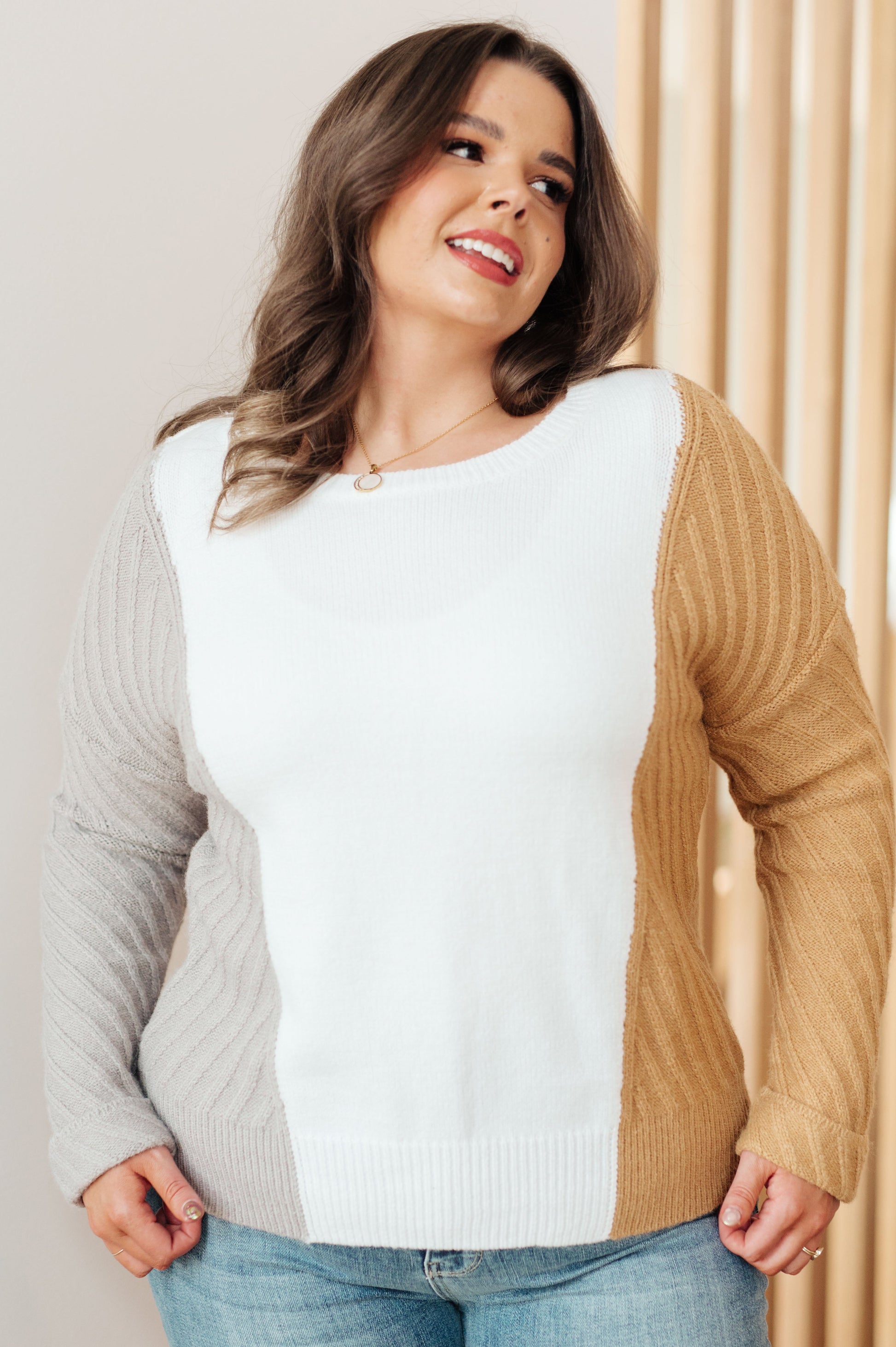 Woman wearing a color-blocked sweater with white, gray, and beige sections.