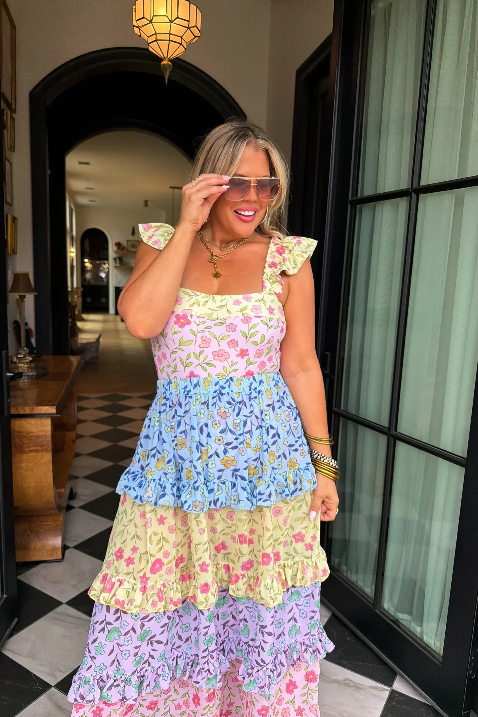 Woman wearing a colorful floral dress in an indoor setting.