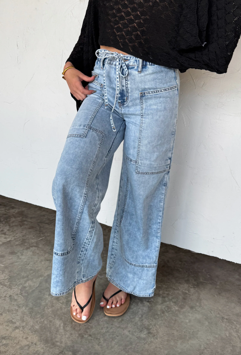 Person wearing light blue wide-leg jeans with a plain background