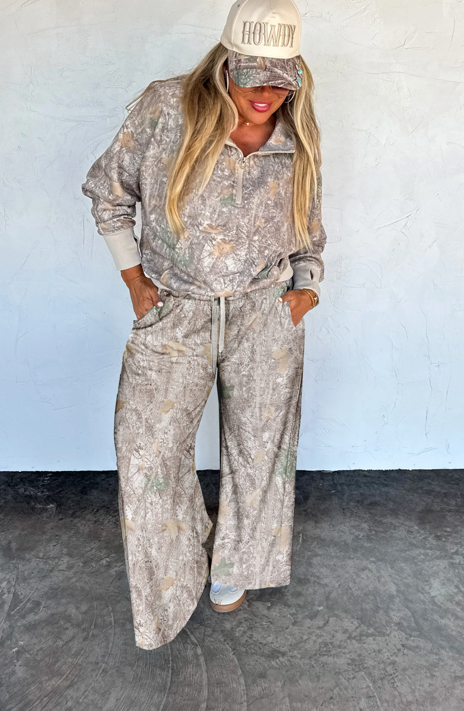 Woman wearing a patterned outfit with a cap against a plain background